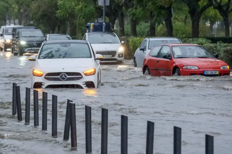 Carros submersos em rua inundada.